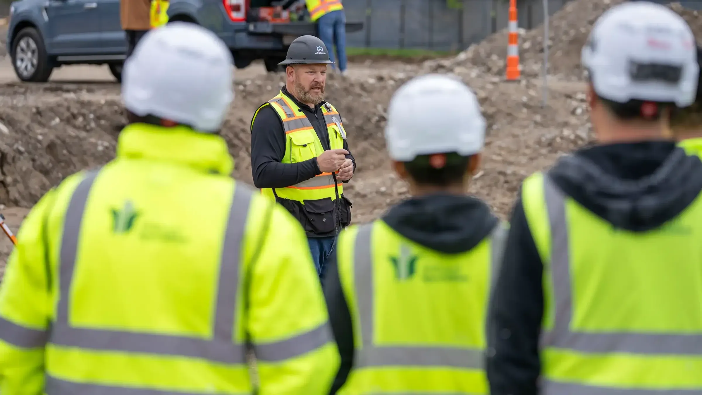 A Westland superintendent leading a toolbox talk with a crew in hard hats and high-visibility vests