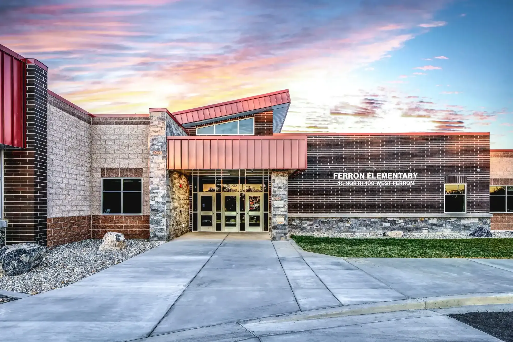 Front entrance of Ferron Elementary at sunset, with a red metal canopy and brick and stone walls
