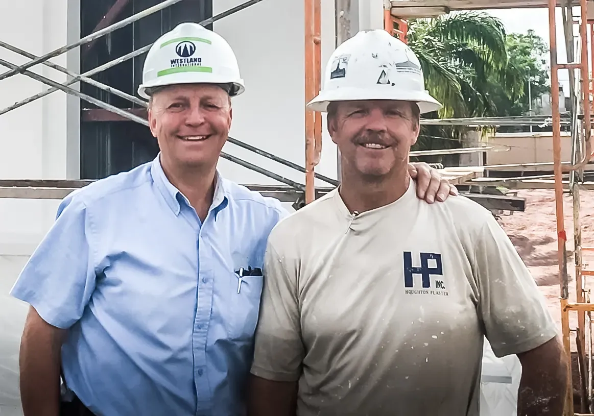 Two men in white hard hats, one bearing the Westland International logo, on a job site in Africa