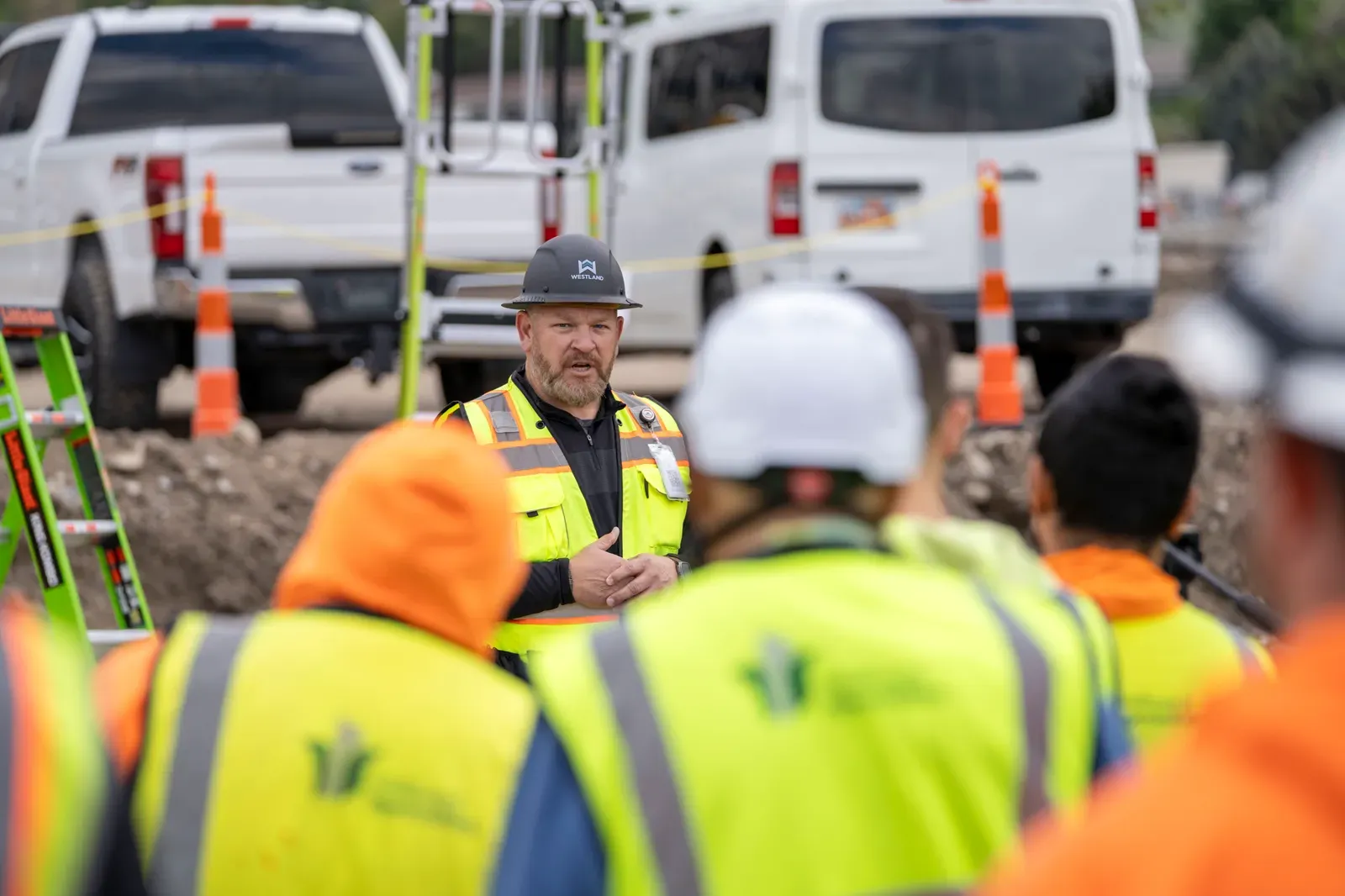 Superintendent leading a toolbox talk with crews in full PPE